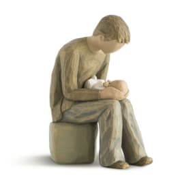 Wooden figurine of a seated person holding a baby
