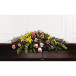 Casket spray with pink and purple roses and yellow lilies