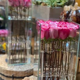 Tall glass vase of pink roses with submerged stems in a modern vertical design