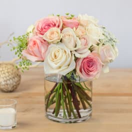 Pink and white roses arranged in a clear glass vase
