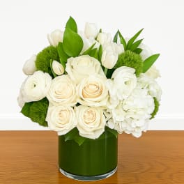White roses and tulips in a green glass vase with bright green accents