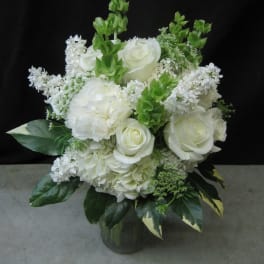 White roses and hydrangeas arranged in a glass vase