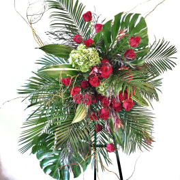 Tall tropical arrangement with red roses and large palm leaves