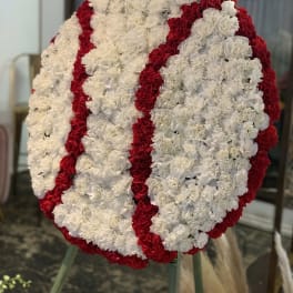 Large circular floral wreath of white and red carnations on an easel