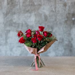 Bouquet of red roses wrapped in brown paper with a striped ribbon
