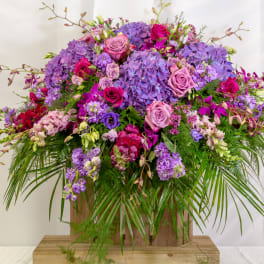 Large arrangement of purple hydrangeas and pink roses in a wooden container