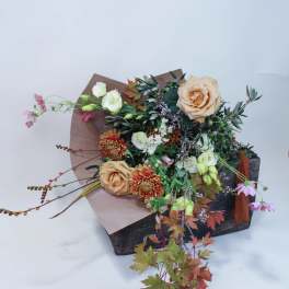Bouquet of peach roses and mixed flowers in a rustic box