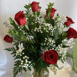 Red roses arranged in a clear glass vase with white baby's breath
