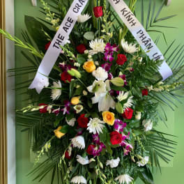 Large funeral wreath with mixed flowers and white condolence ribbons