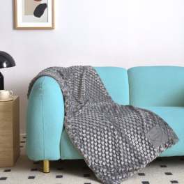 Gray textured throw blanket draped over a turquoise sofa