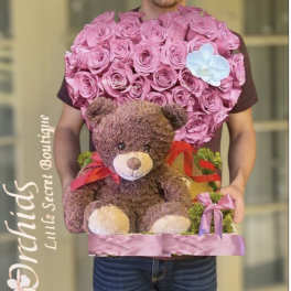 Heart-shaped pink rose arrangement with a teddy bear and ribbon accents