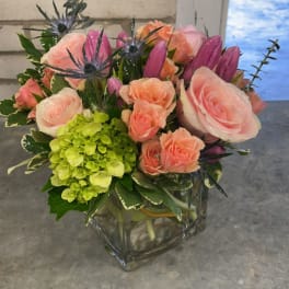 Pink roses and purple buds in a square glass vase