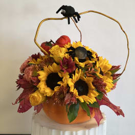 Pumpkin-shaped floral arrangement with sunflowers and black spider decorations