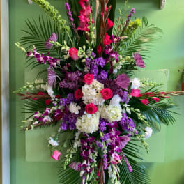 Tall floral spray with pink, purple, and white flowers on palm fronds