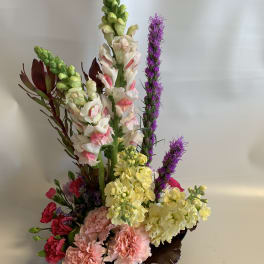 Tall mixed floral arrangement with pink, yellow, white, and purple blooms