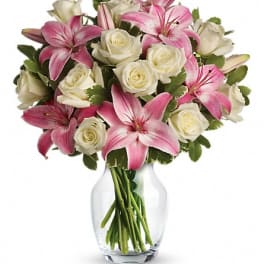Pink lilies and white roses arranged in a clear glass vase