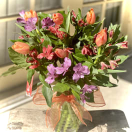 Bouquet of orange tulips and purple alstroemeria in a glass vase