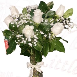 White roses and baby's breath in a glass vase with a ribbon