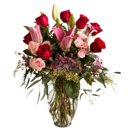Bouquet of red roses and pink lilies in a clear glass vase