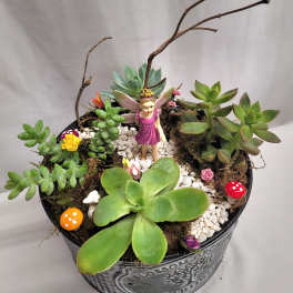 Succulent arrangement in a metal pot with a small fairy figurine