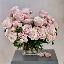 Pink roses and spray roses arranged in a clear glass vase