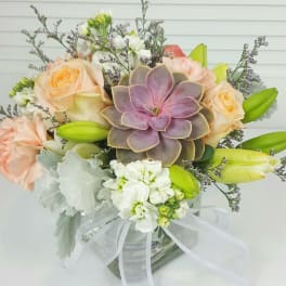 Bouquet with roses, lilies, and a succulent in a glass vase