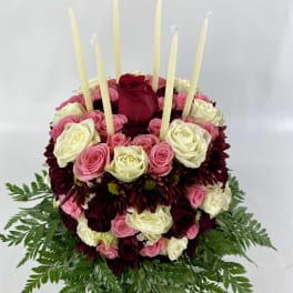 Round rose arrangement with tall taper candles and fern foliage