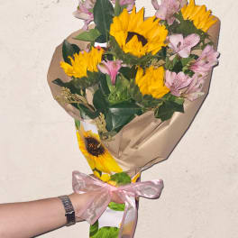 Bouquet of yellow sunflowers and pink alstroemeria wrapped in paper