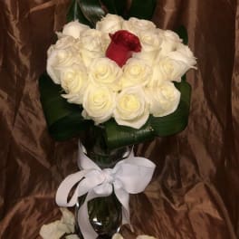 Bouquet of white roses with one red rose in a glass vase