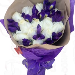 Bouquet of white roses and purple irises wrapped in brown and purple paper