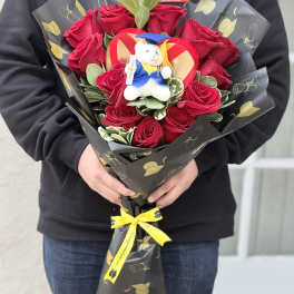 Bouquet of red roses with a small teddy bear in graduation attire