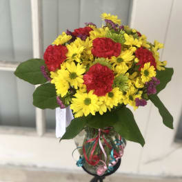 Bouquet of yellow daisies and red carnations in a glass vase
