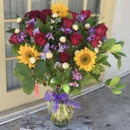 Bouquet of red roses and yellow sunflowers in a glass vase