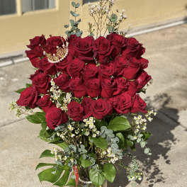 Bouquet of red roses in a glass vase with small white filler flowers