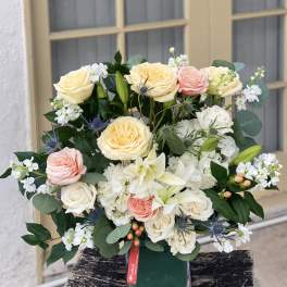 Bouquet of cream, pink, and white roses in a glass vase