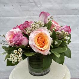 Pink and peach roses arranged in a glass vase