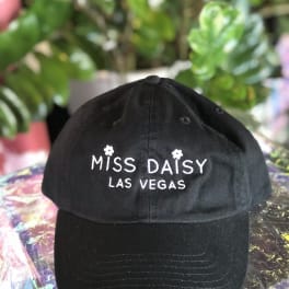 Black baseball cap with white "Miss Daisy Las Vegas" embroidery