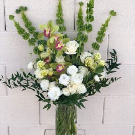 White and pale green floral arrangement in a clear glass vase