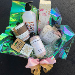 Bath and body gift basket with bottles, jars, and a pink bow
