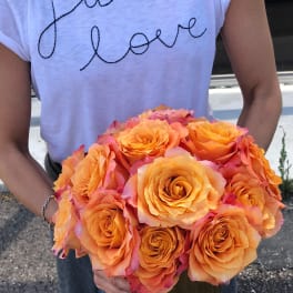 Person holding a bouquet of orange roses in a vase