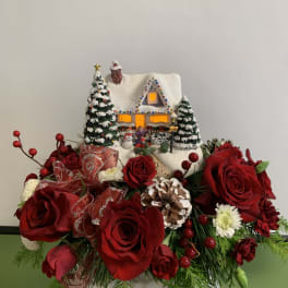 Christmas floral arrangement with red roses and a snowy house decoration