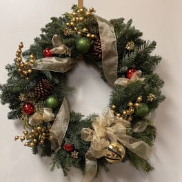 Christmas wreath with gold ribbon, ornaments, and pinecones