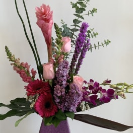 Tall mixed bouquet with pink and purple flowers in a purple vase