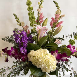 Tall mixed bouquet with hydrangea, lilies, orchids, and snapdragons in a glass vase