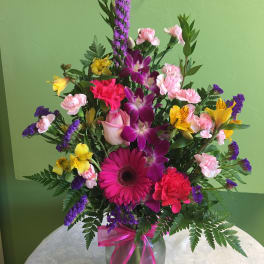 Mixed bouquet in a glass vase with pink, purple, and yellow flowers