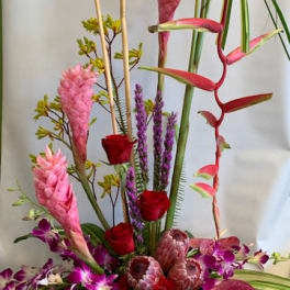 Tall tropical floral arrangement with pink and red blooms in a container