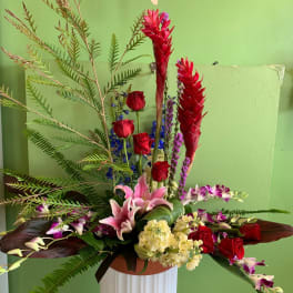 Tall floral arrangement with red roses, pink lilies, and purple orchids in a vase