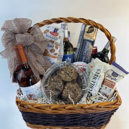 Gift basket with wine, snacks, and cookies in a wicker basket