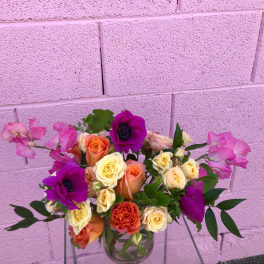 Mixed bouquet of roses and purple anemones in a clear glass vase