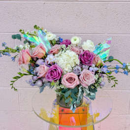 Bouquet of pink and purple roses with white blooms in a glass vase